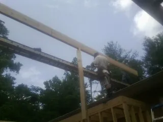 Carpenter setting a ridge beam over a new addition frame — Ice Dam Removal by Roofing Brothers in Clayville