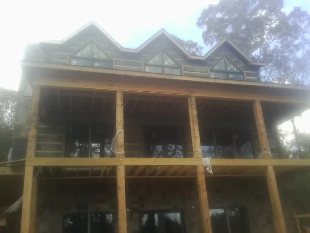 Dormers and porch framing on a large log home under construction — Roof Coating work by our crew in Clayville